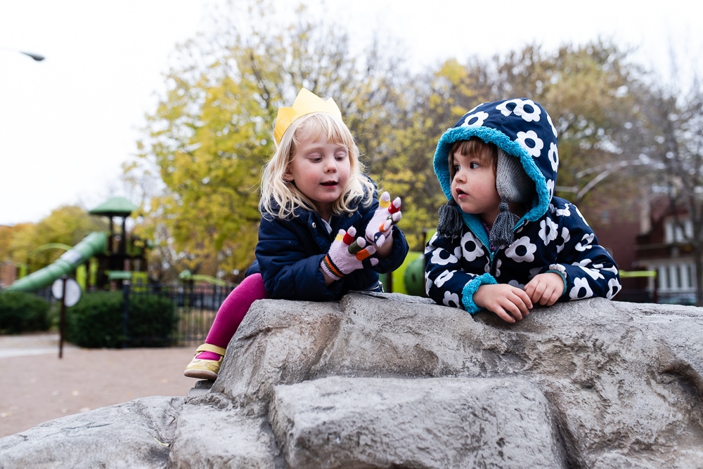 Two children sitting on a rock in the park