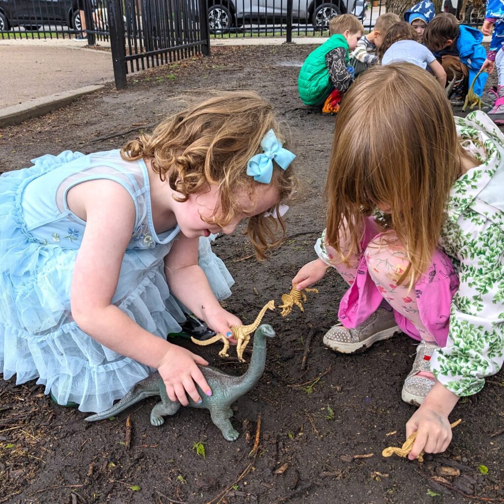 Children play with dinosaurs in the mud.